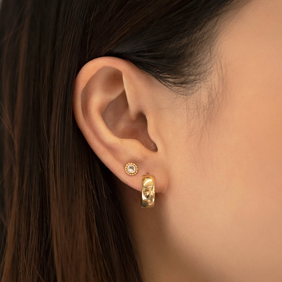 Gold vermeil beaded halo stud with a clear stone shown on a model's lobe with a hoop