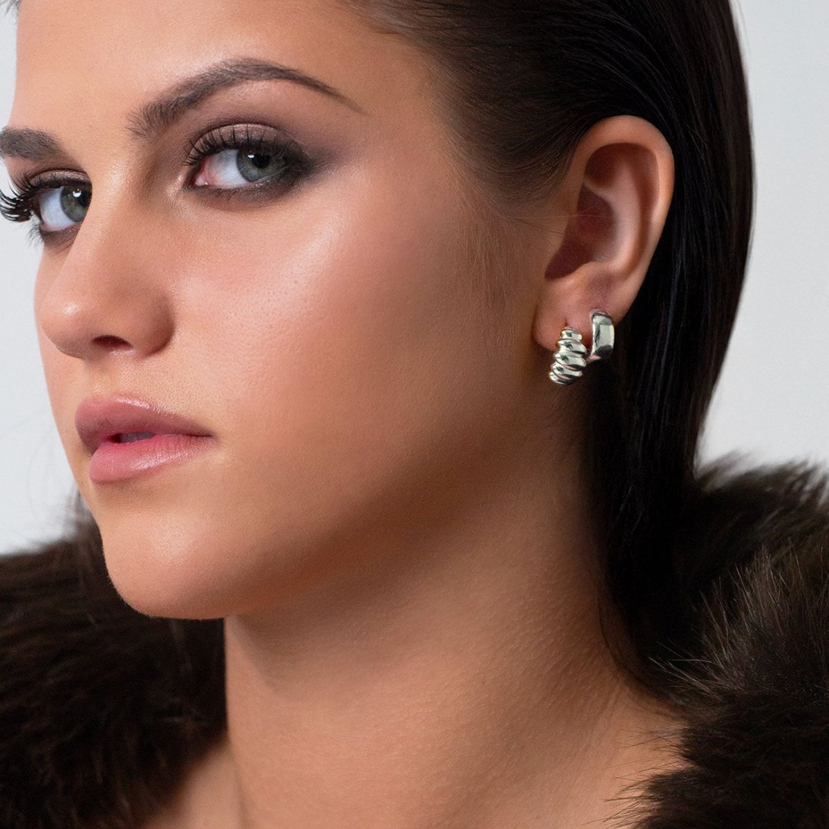 Sterling silver croissant dome stud earring shown on a model's lobe in profile