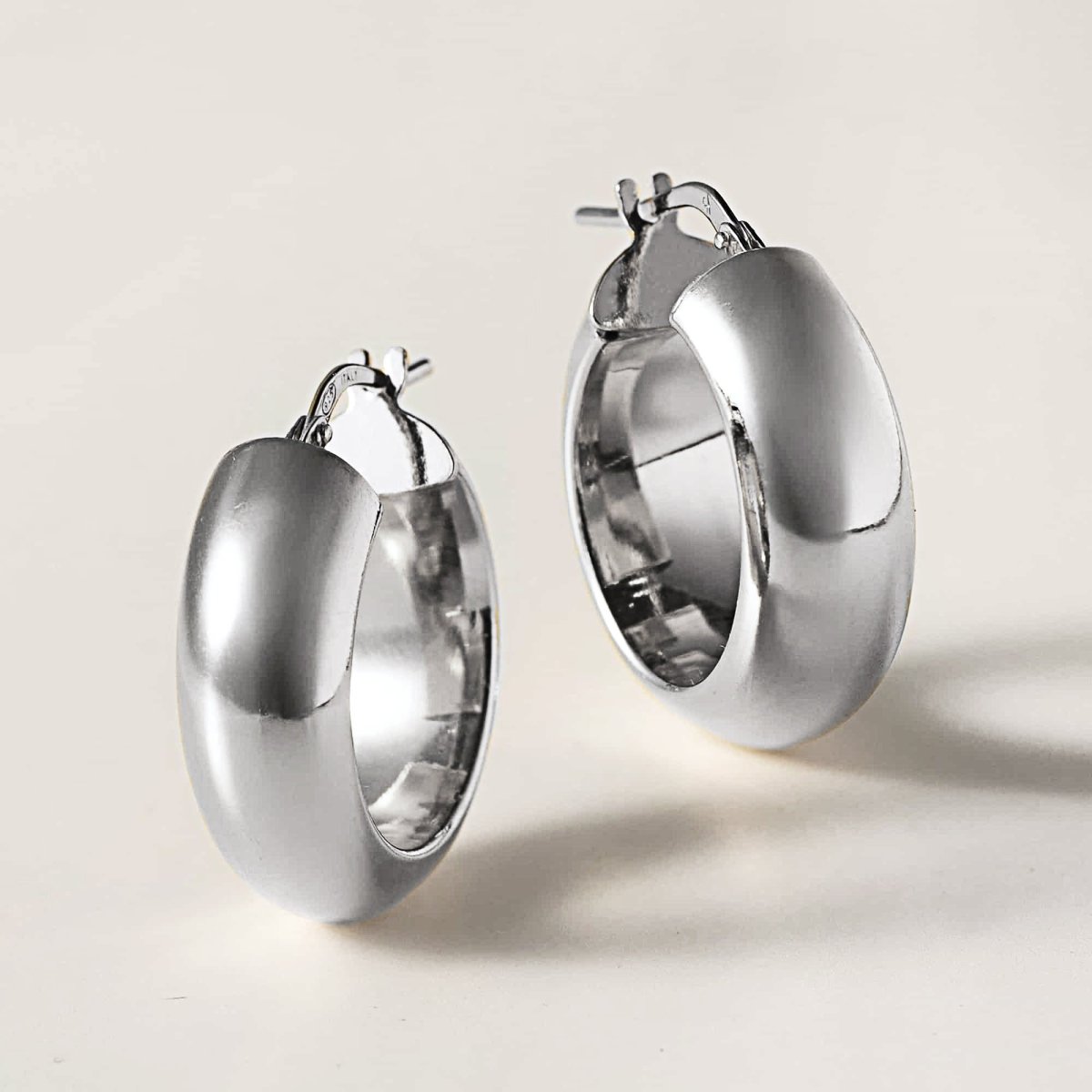 Sterling silver chunky hoop earrings angled to show width, on a white background