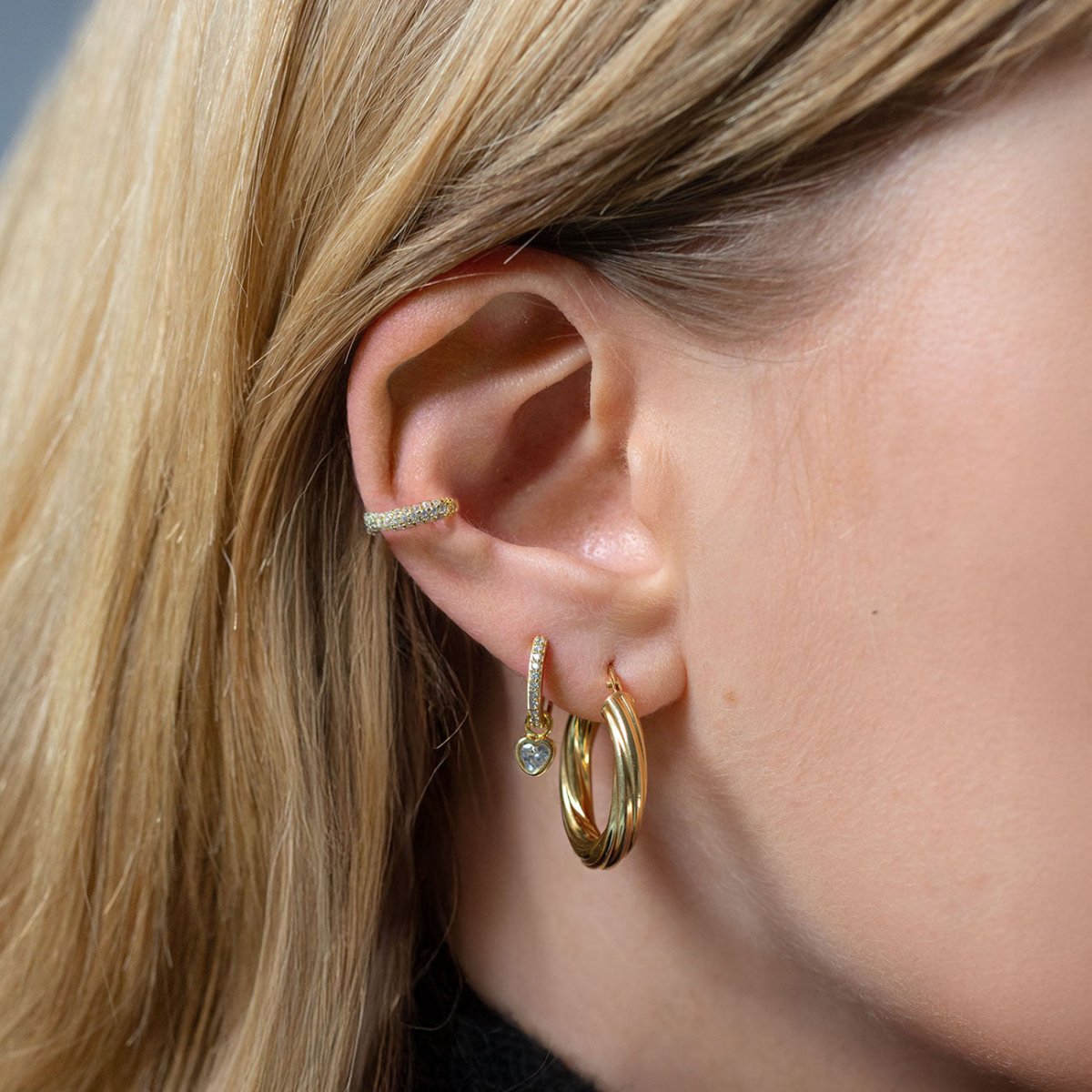 Gold vermeil pavé huggie with a bezel-set aquamarine heart charm, shown on a model's lobe