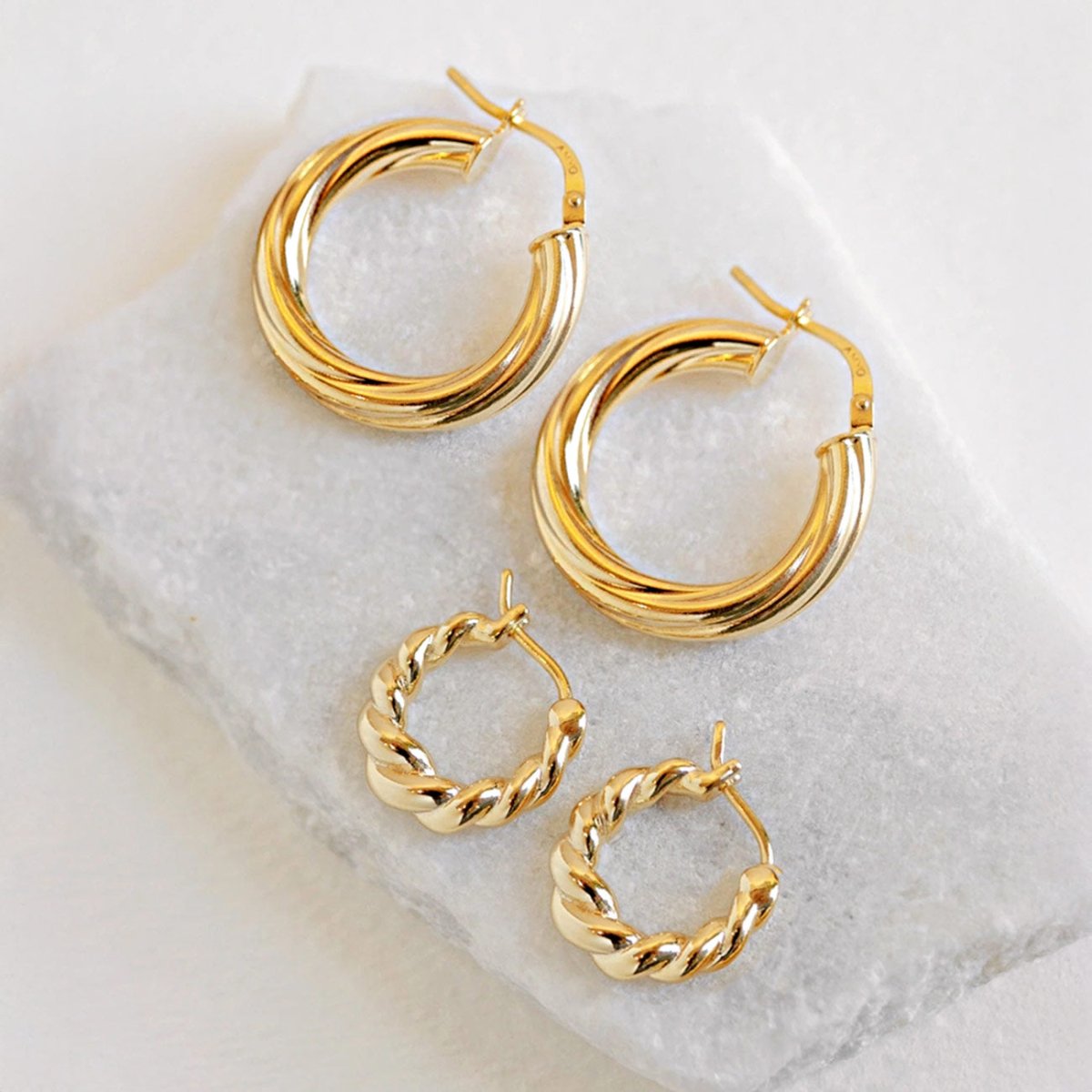 Gold vermeil twisted hoop earrings in two sizes, large and small pairs on white marble