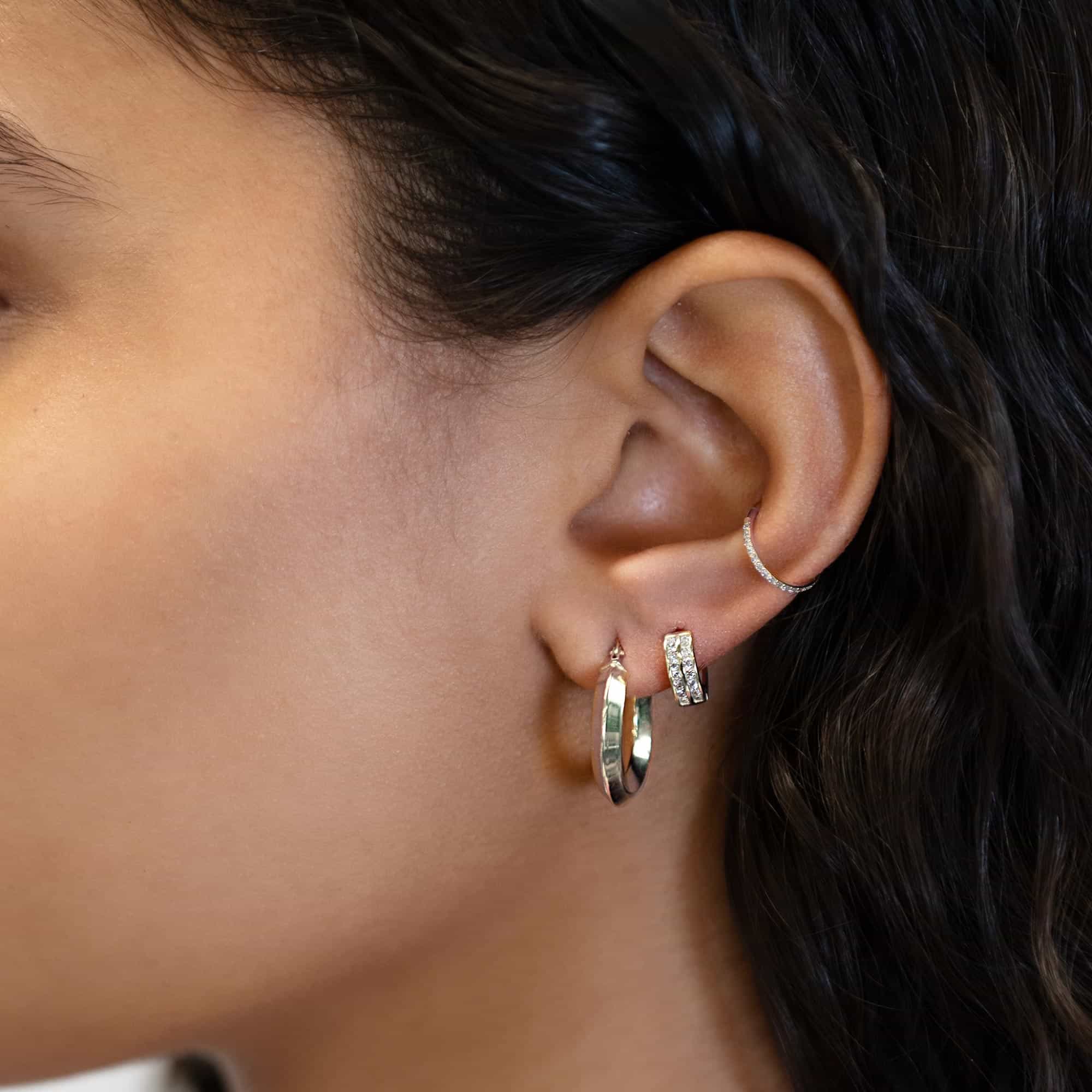 Silver hoop and clear-stone pave huggie styled together on a model's ear