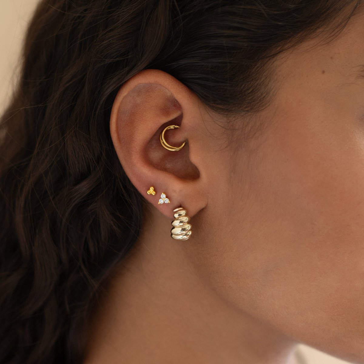 Gold vermeil three-stone white zirconia flat back stud shown in a model's lobe