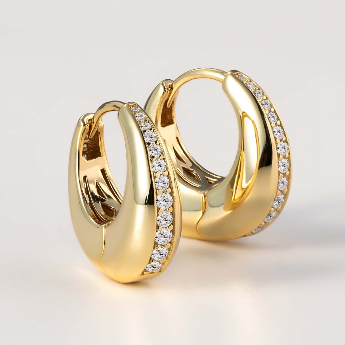 Gold vermeil chunky huggie hoops with a pavé zirconia inlay, close-up detail on a pale background