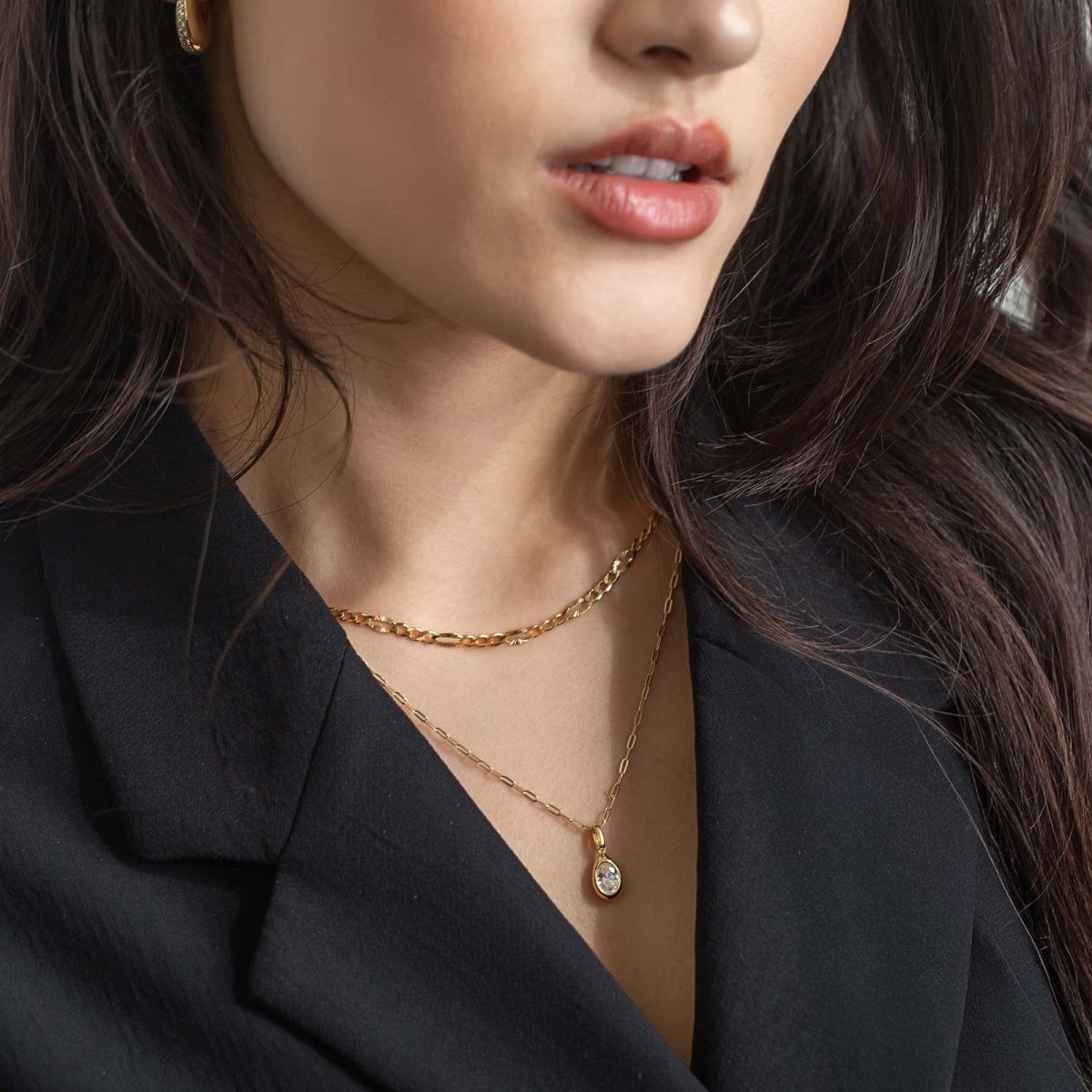 Gold vermeil figaro chain necklace layered with a clear-stone pendant, shown on a model's neckline