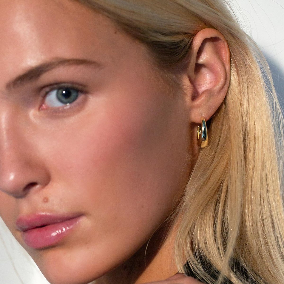 Gold vermeil tapered C-shaped huggie hoop shown on a model's lobe