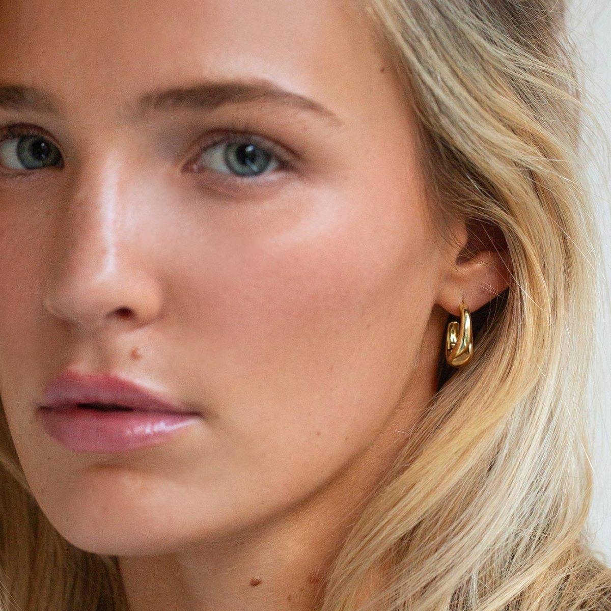 Gold vermeil tapered C-shaped hoop earring shown on a model's lobe