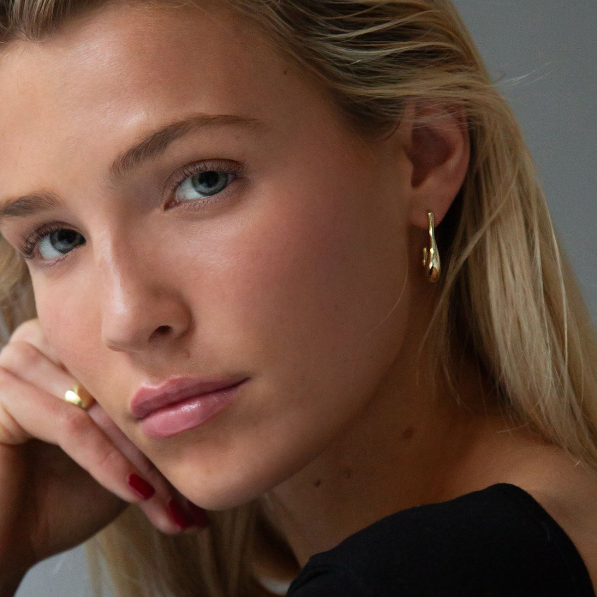 Gold vermeil sculptural J-hoop earring shown on a model's ear and lobe