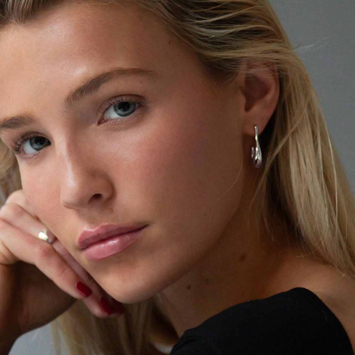 Sterling silver sculptural J-hoop earring shown on a model's ear and lobe