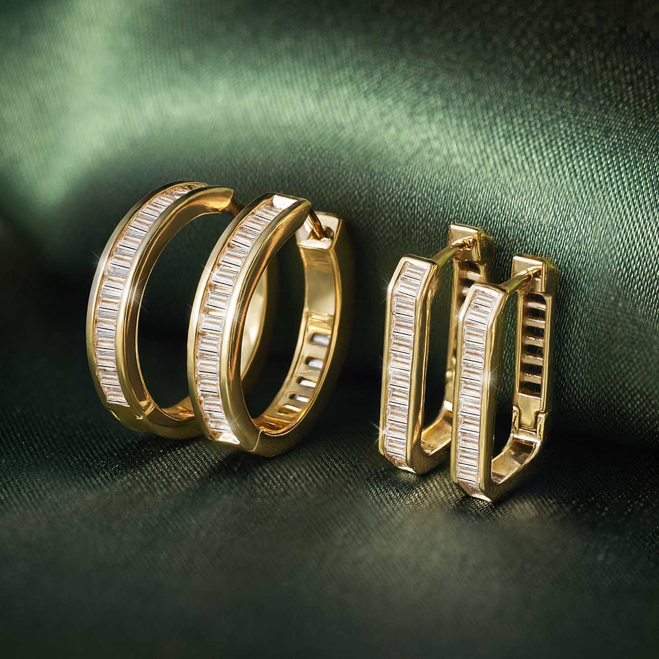 Gold vermeil baguette and oval huggie hoops with clear stones, grouped on green satin
