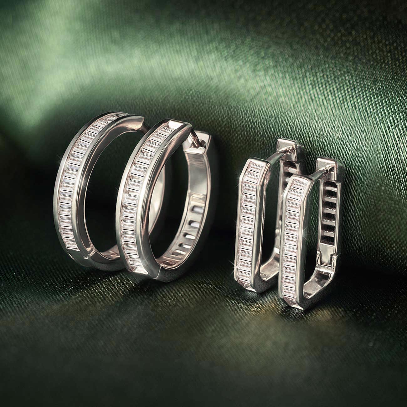 Sterling silver baguette and oval huggie hoops with white zirconia, grouped on green satin