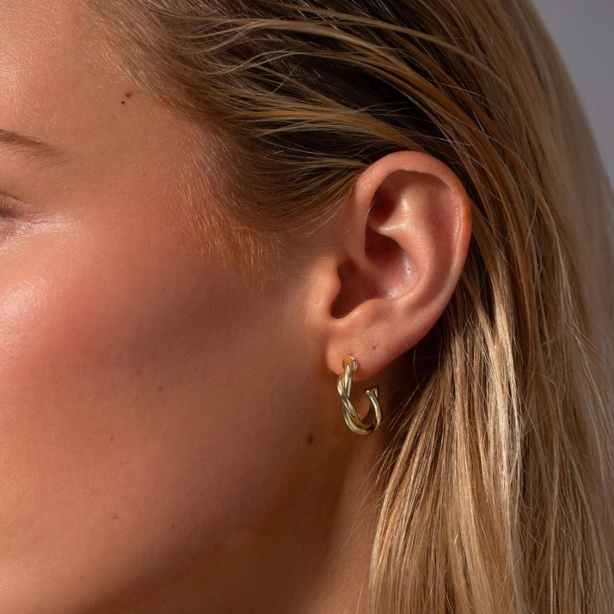 Gold vermeil twisted rope C-hoop earring shown close on a model's lobe