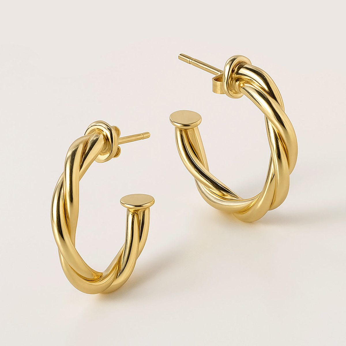 Gold vermeil twisted rope C-hoop earrings, close-up detail of the open hoop and posts on a cream background