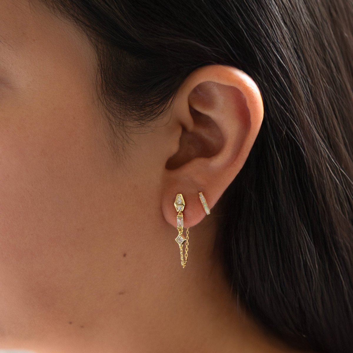 Gold vermeil chain drop earring with baguette and square clear stones, shown on a model's lobe