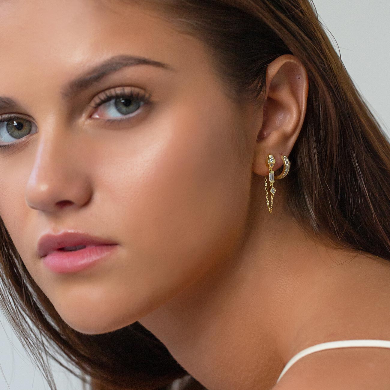 Gold vermeil chain drop earring with clear stones, shown on a model's ear with a small hoop