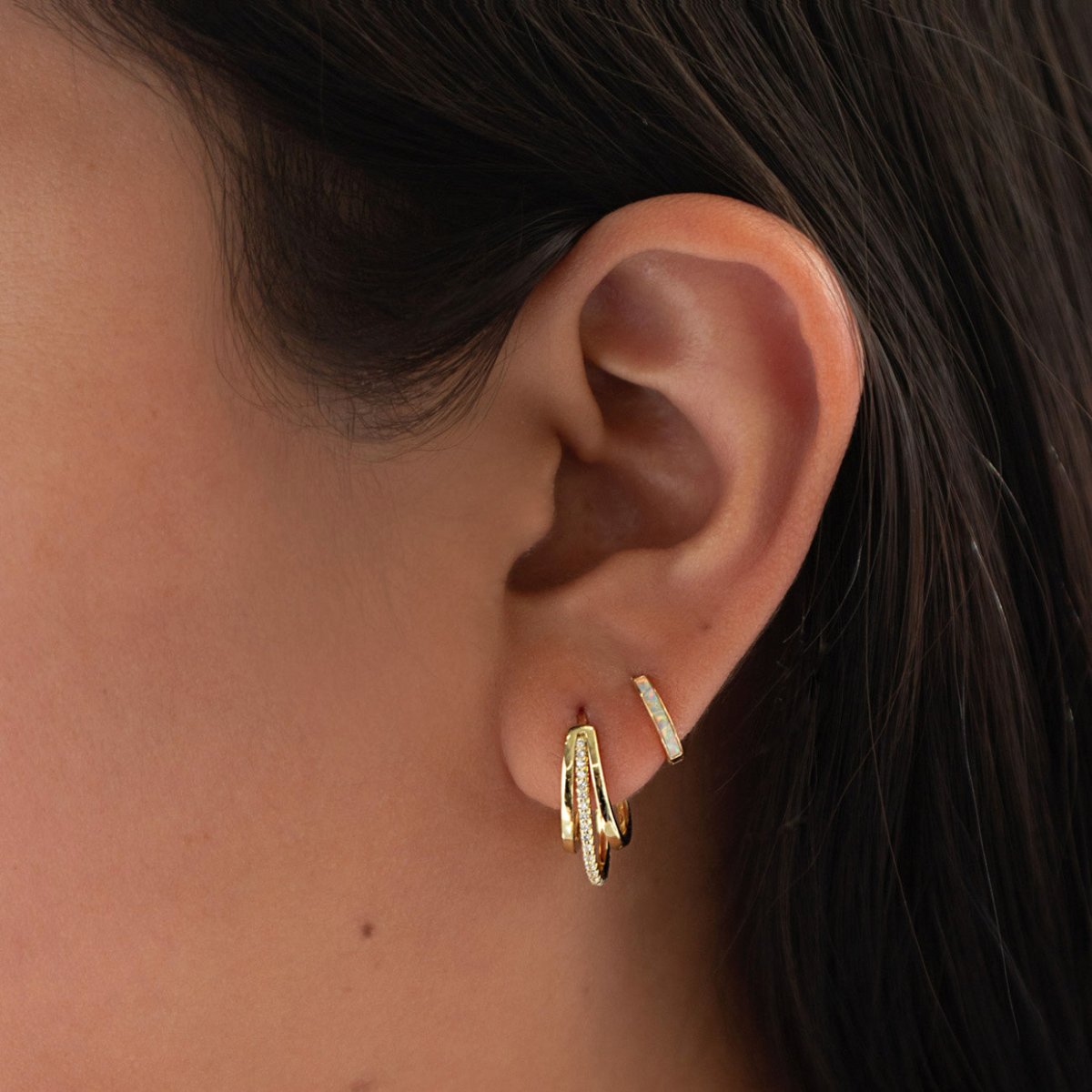 Gold vermeil pave triple mini hoop with clear crystals, shown on a model's lobe