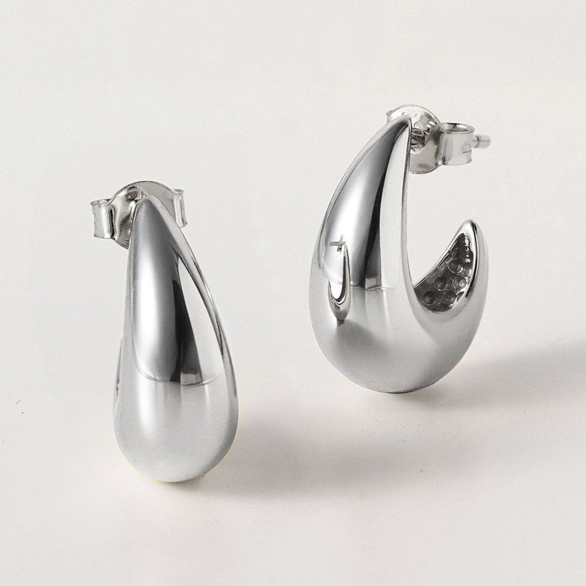 Sterling silver chunky tapered teardrop hoop earrings, shown as a pair on a white background