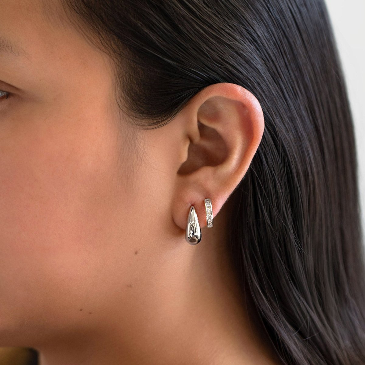 Sterling silver chunky tapered teardrop hoop earring, shown on a model's lobe