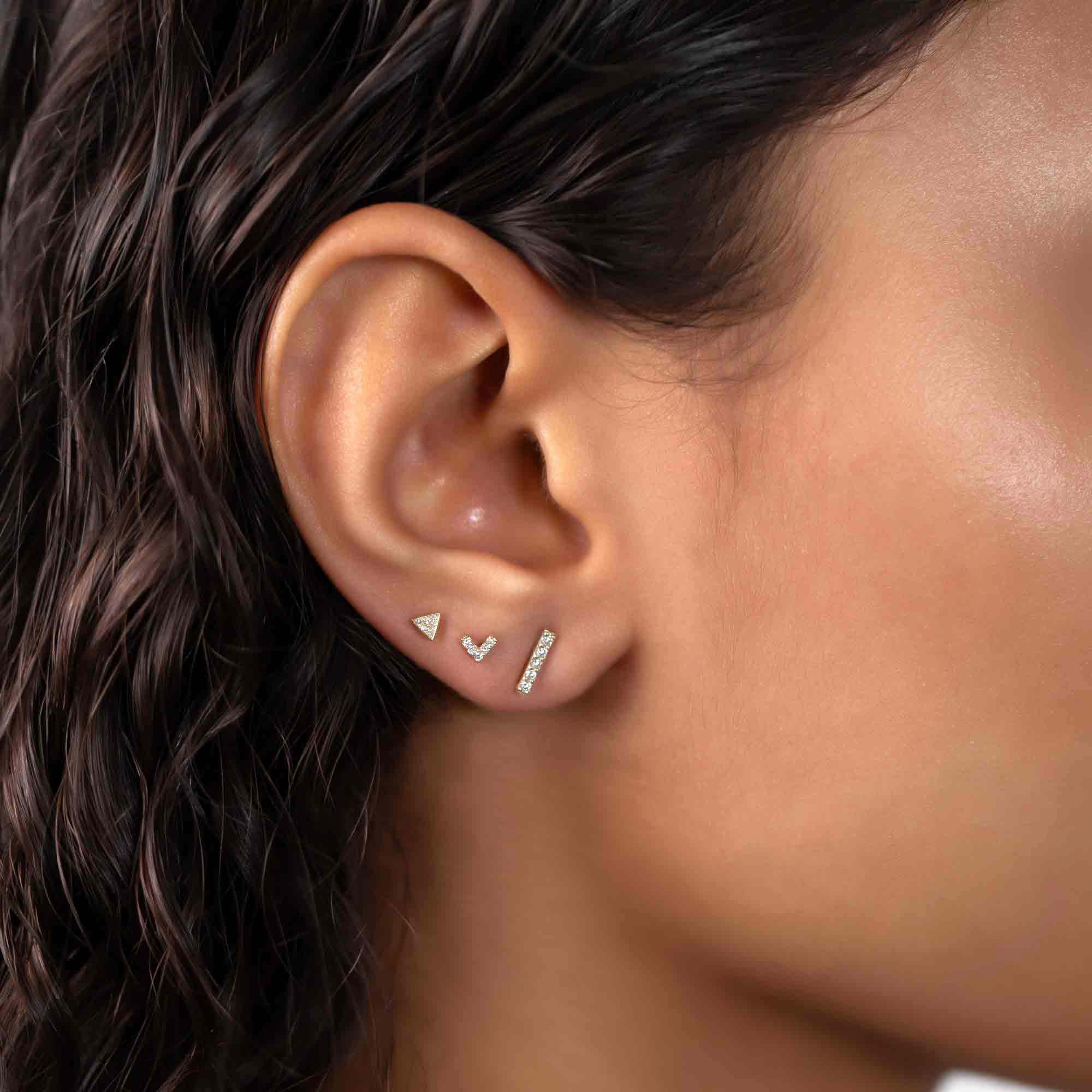 14K white gold pavé triangle stud with clear stones, close-up on a model's lobe in a stack