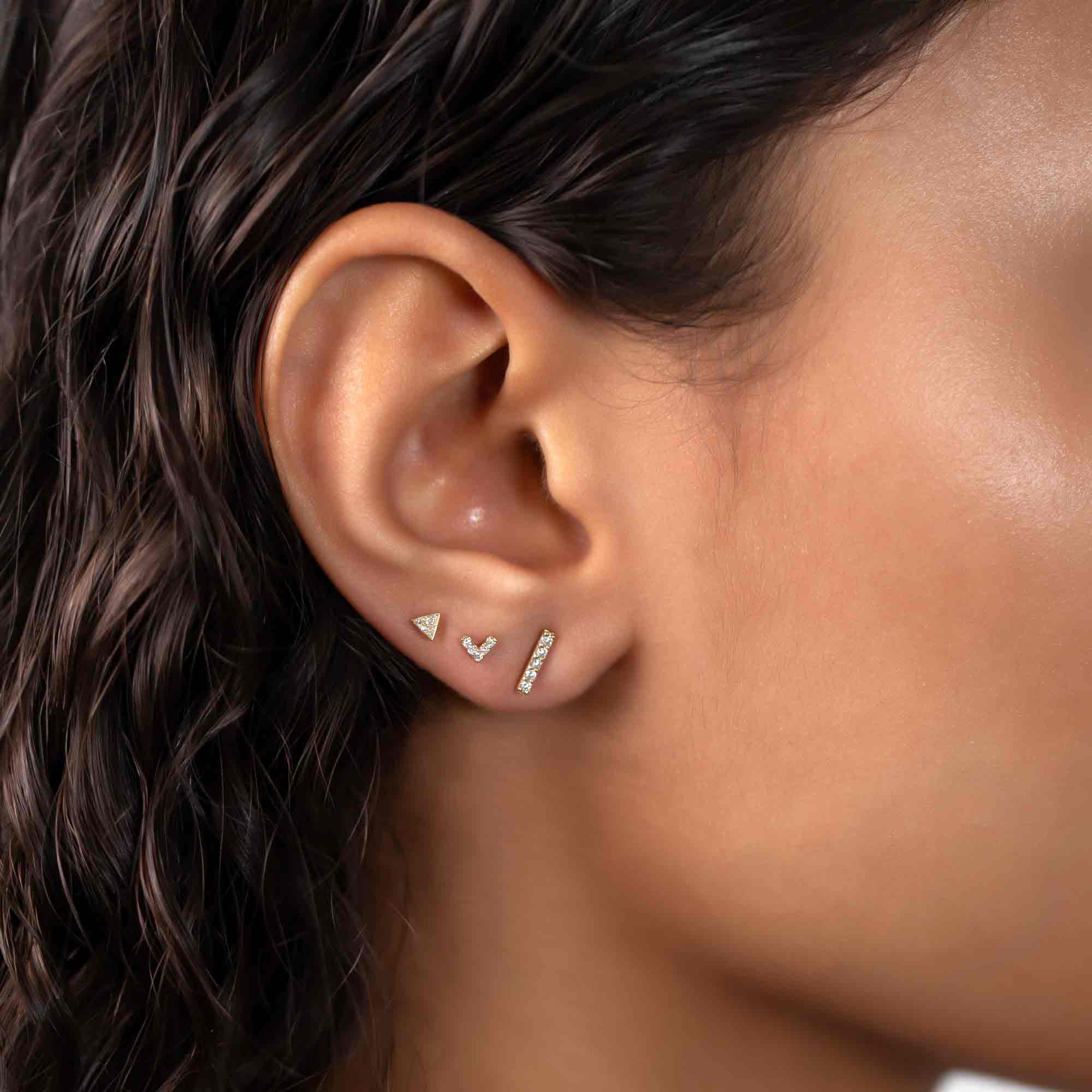 14K gold pavé triangle stud with clear stones, shown in an ear stack on a model's lobe