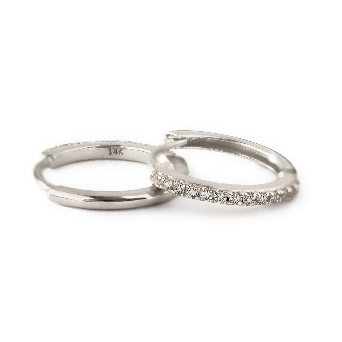 14K white gold diamond huggie hoops showing pave row and 14K stamp, on a white background