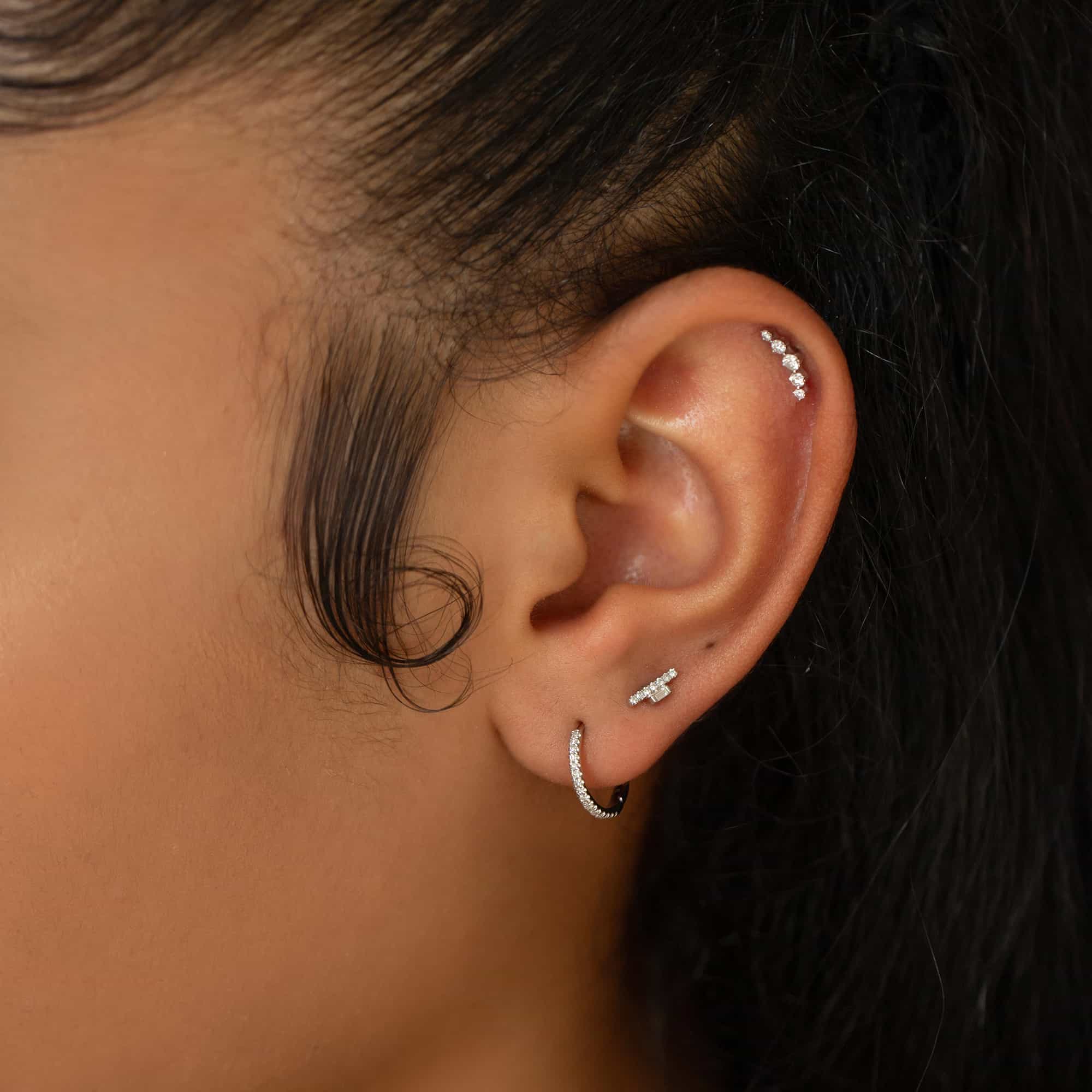 14K white gold diamond bar stud shown in a lobe piercing on a model's ear