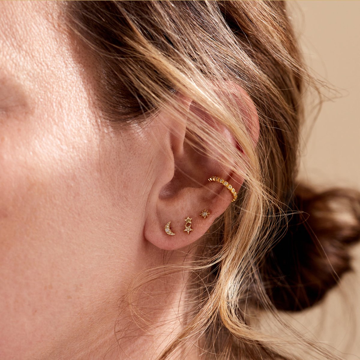 14K gold diamond star studs with a dangling star and crescent moon shown on a model's lobe