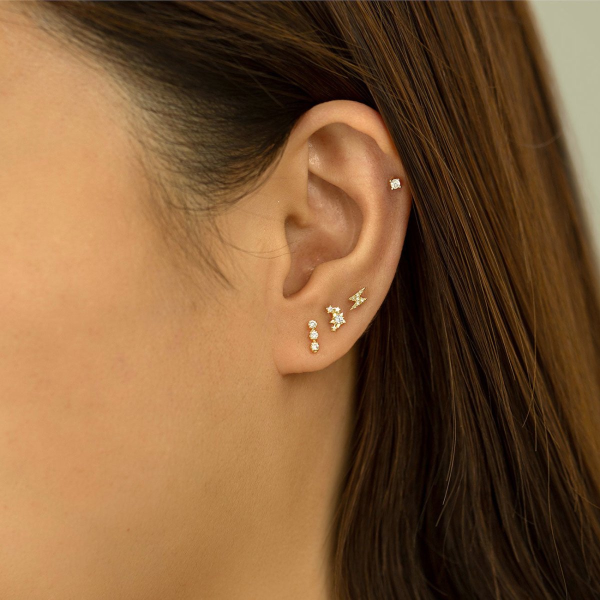14K gold diamond lightning bolt stud in an ear stack with cluster and bezel studs