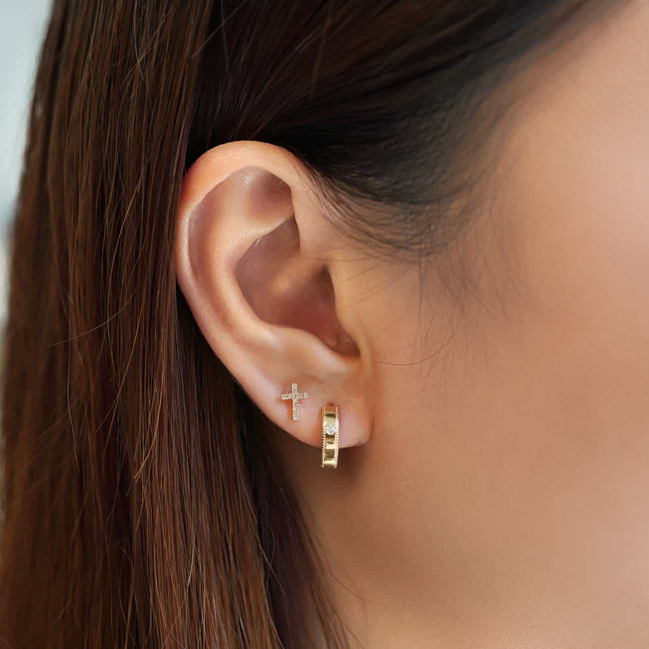 14K gold pave diamond cross stud paired with a milgrain hoop, shown on a model's lobe