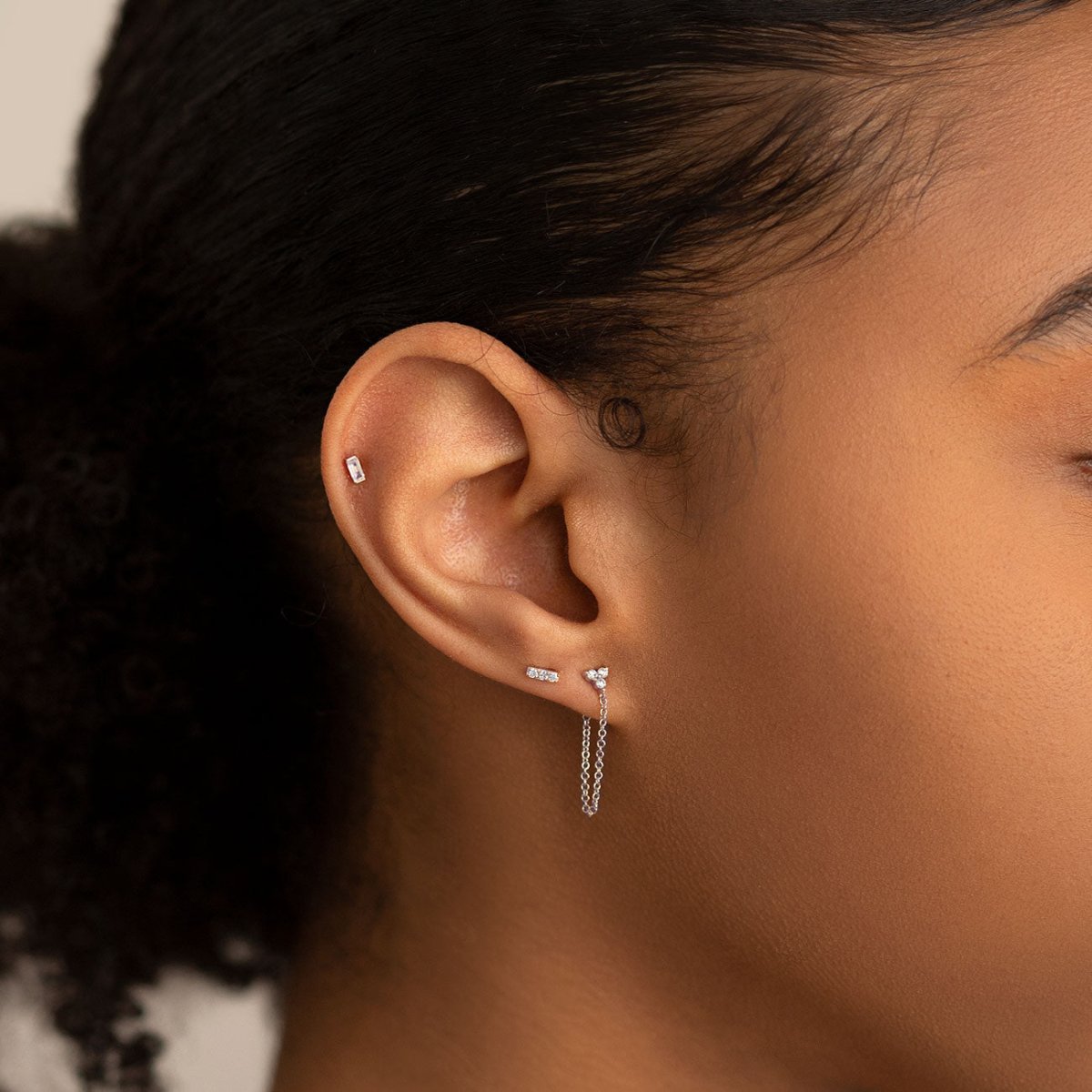 Sterling silver crystal baguette flatback stud shown on a model's upper lobe with a chain-link lobe stud