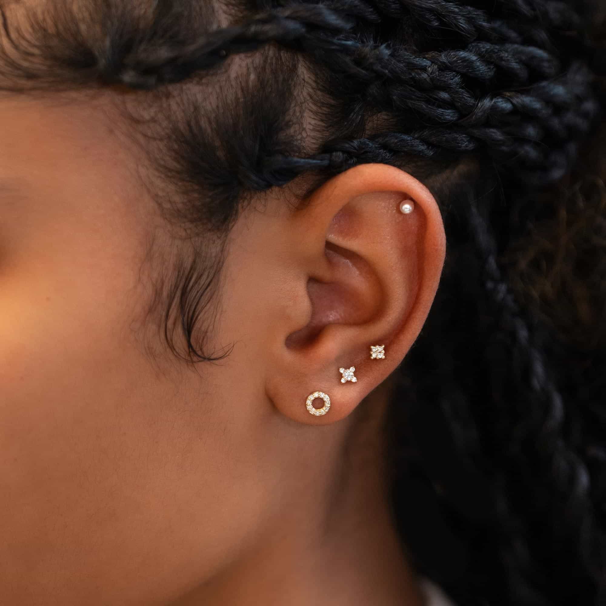 14K gold diamond open-circle stud shown in a lobe piercing with diamond cluster studs above, on a model's ear