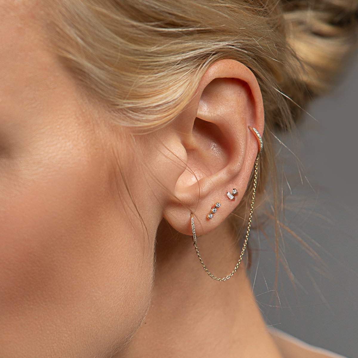 14K gold baguette and round diamond duet studs worn in a model's lobe stack