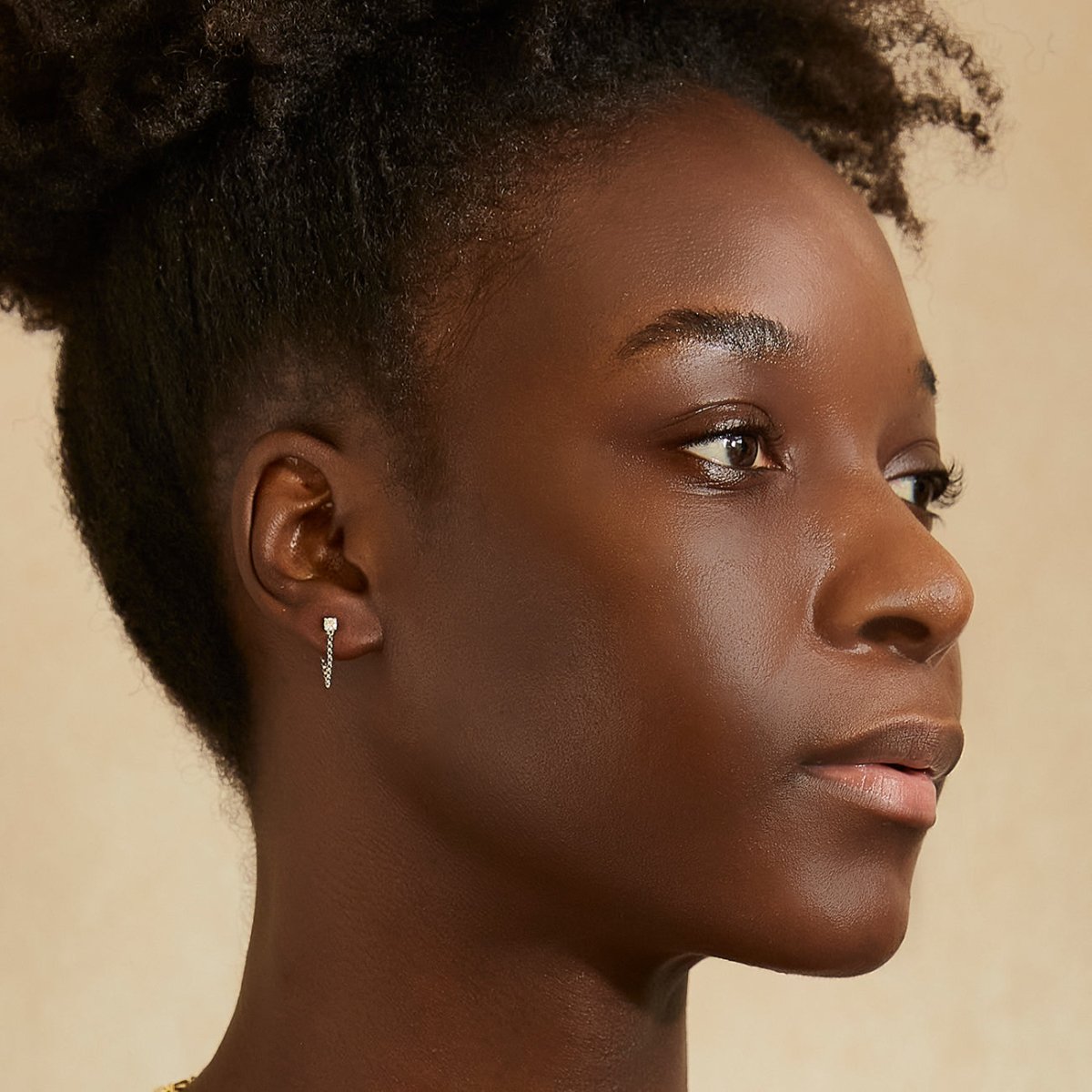 14K white gold diamond stud with a draped chain, shown on a model's lobe