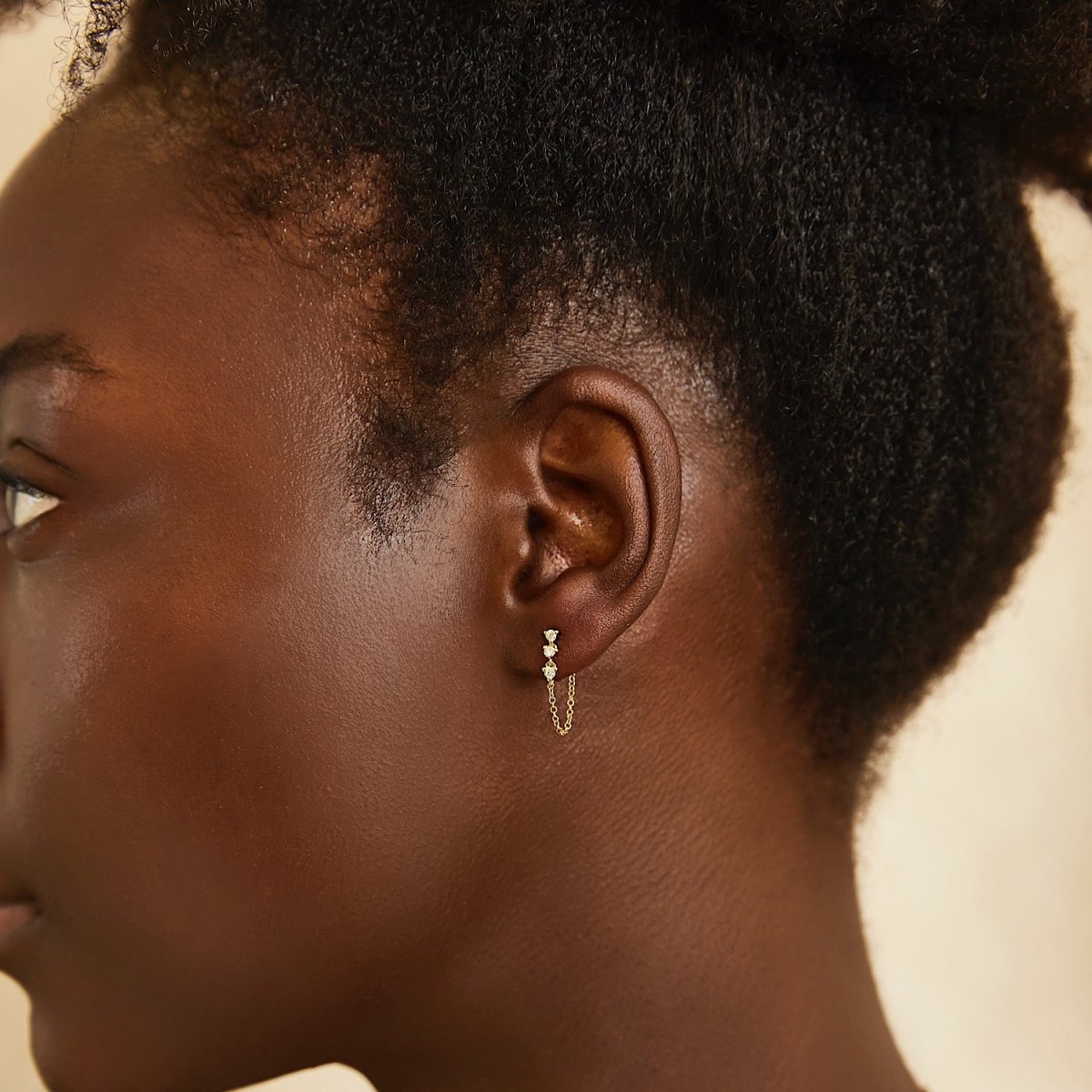14K gold diamond drop chain earrings with a looping chain, shown on a model's ear