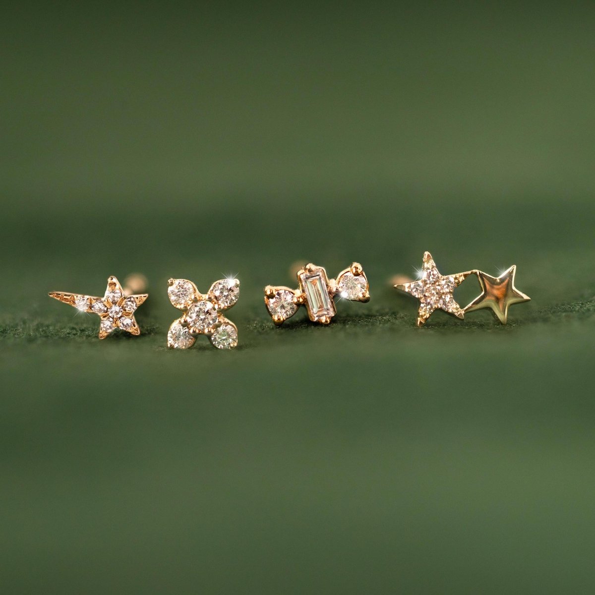 14K gold diamond studs including the fleur design, shown in a row on a green leaf