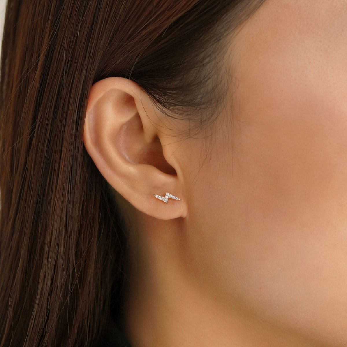 14K white gold lightning bolt pavé stud with clear crystals, shown on a model's lobe