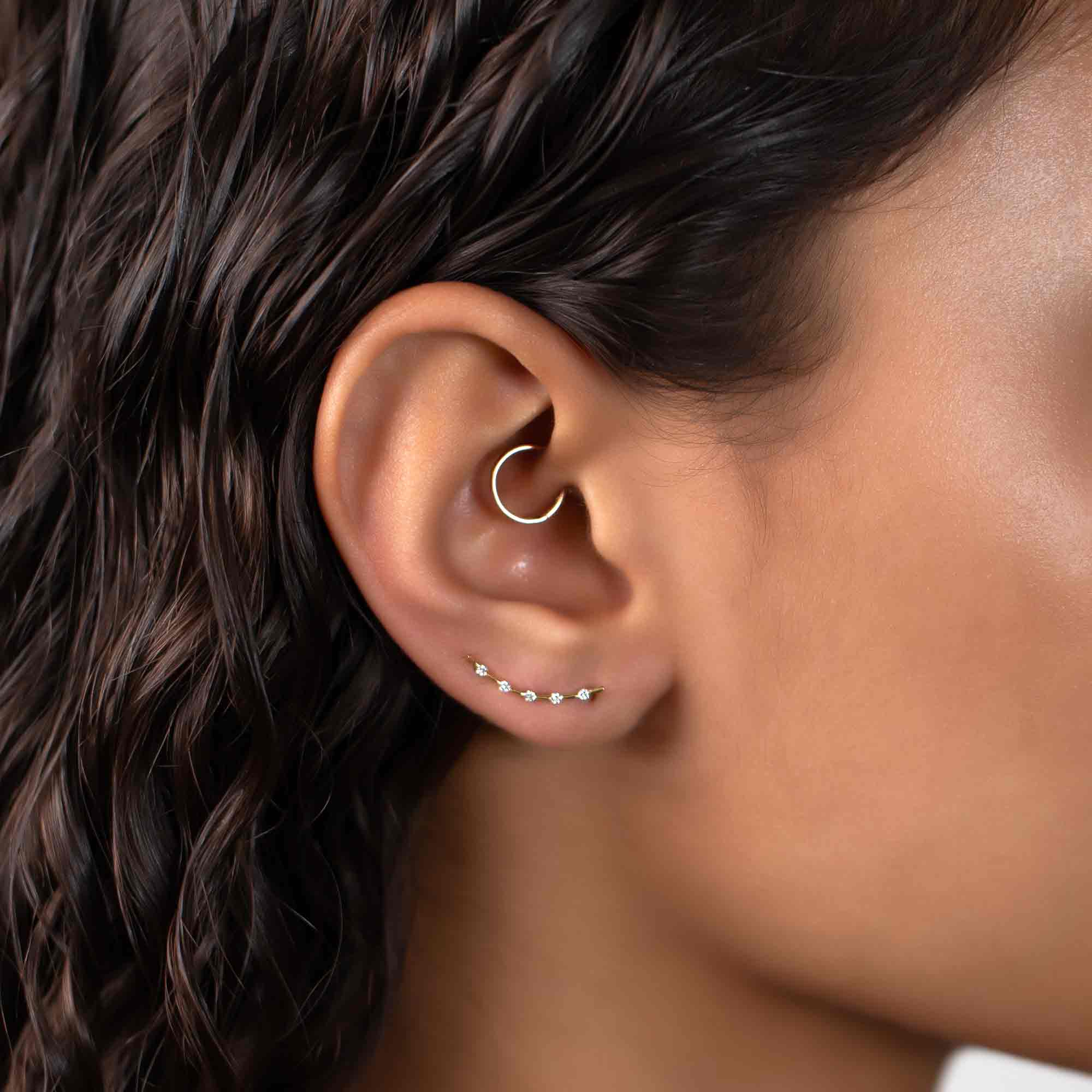 14K gold curved climber earring with clear stones, shown along a model's upper lobe