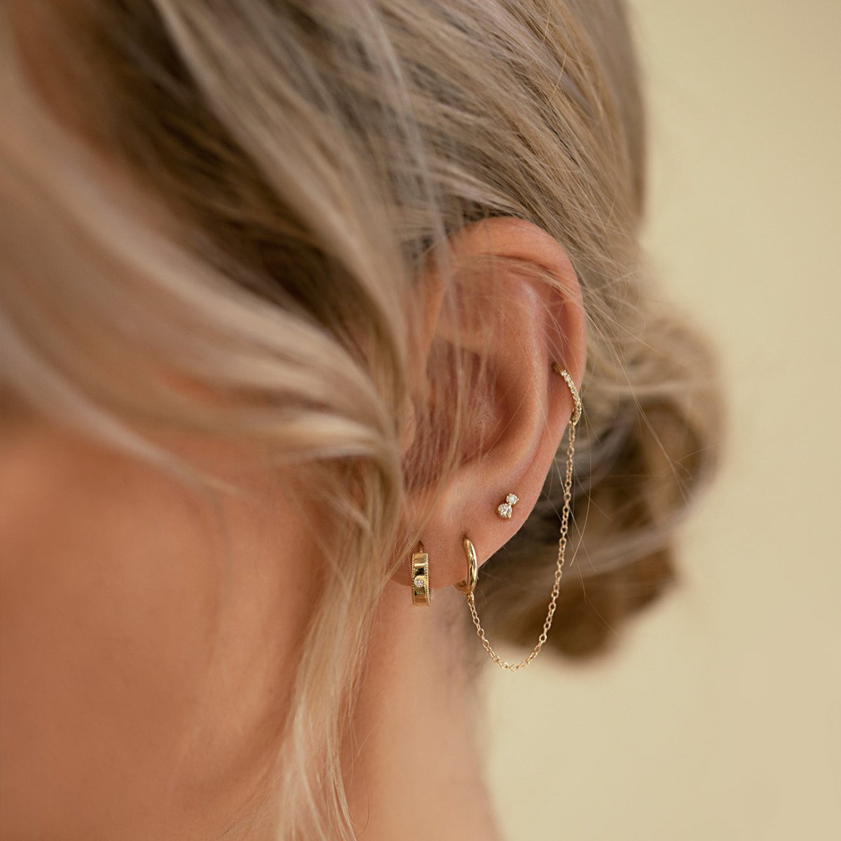 Gold vermeil milgrain band huggie with a clear stone, shown on a model's lobe in a stacked ear
