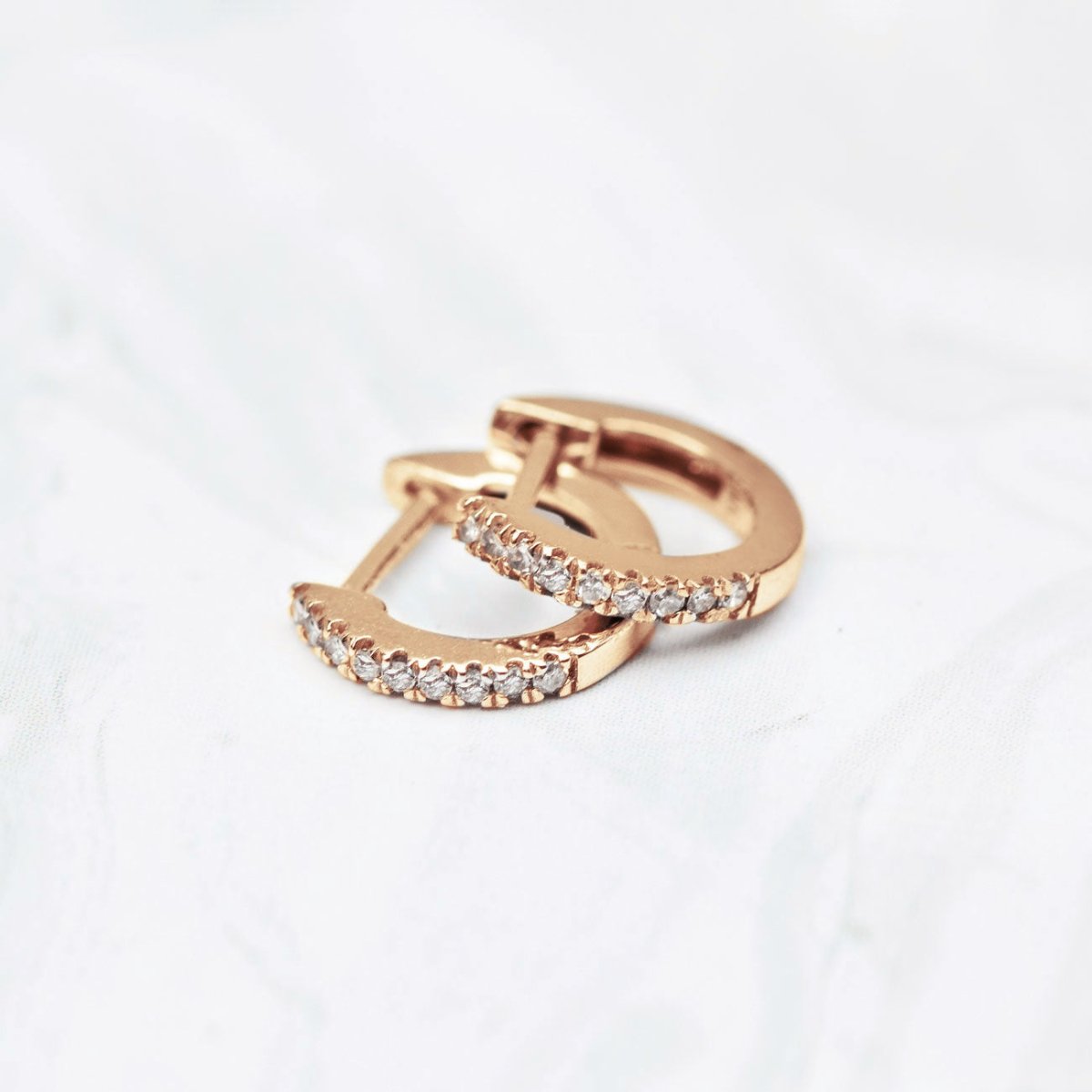 14K rose gold pavé diamond huggie hoops shown in three sizes, on a white background