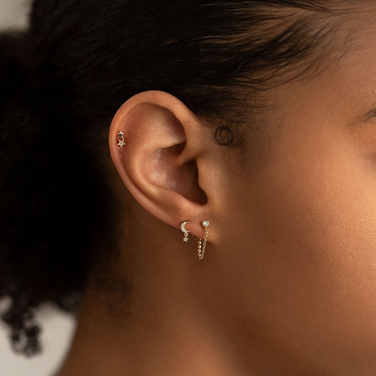 14K gold pavé chain earring with white zirconia stud shown on a model's lobe
