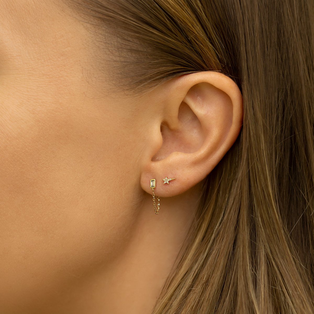 14K gold baguette diamond chain stud, shown close up in a model's lobe piercing