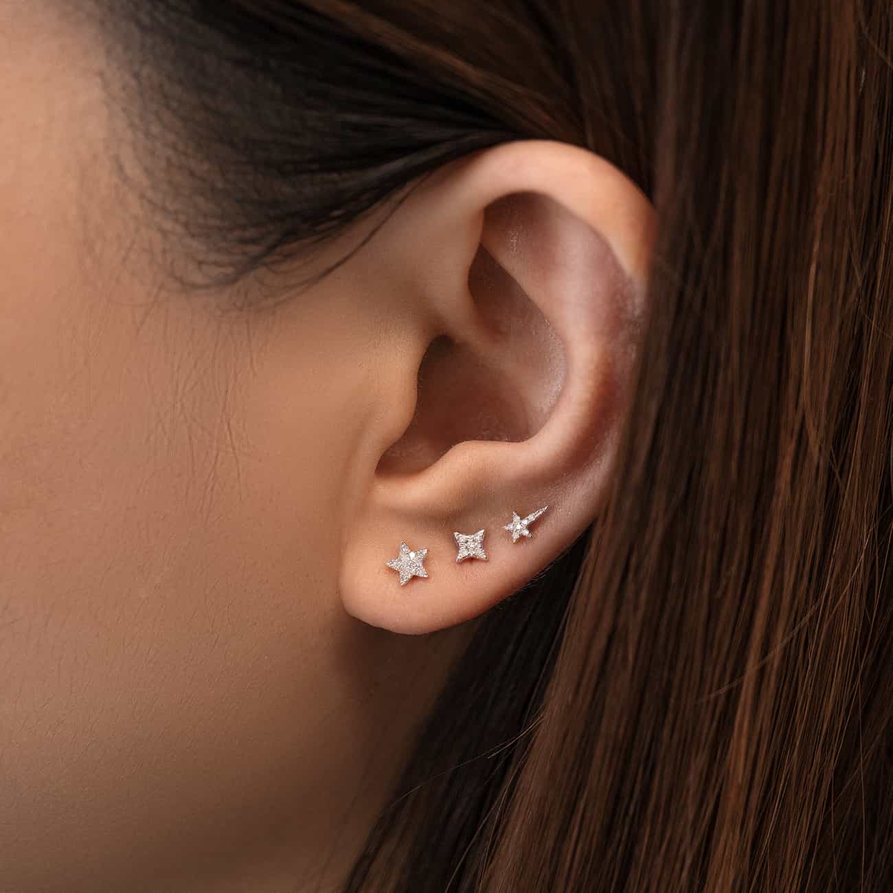 Silver star studs with clear stones lined along the lobe on a model's ear