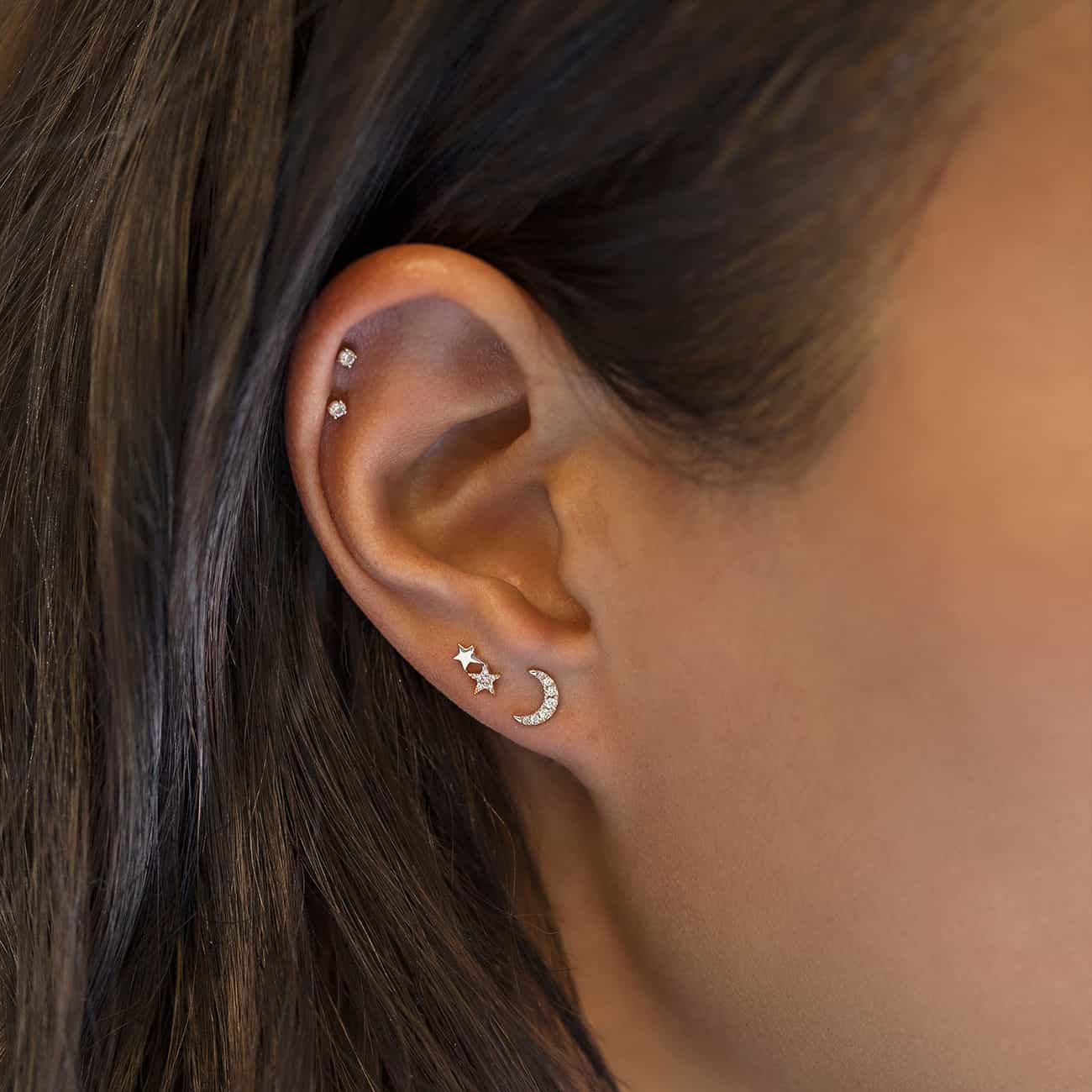 14K white gold tiny diamond star and crescent moon studs shown on a model's lobe and ear cuff