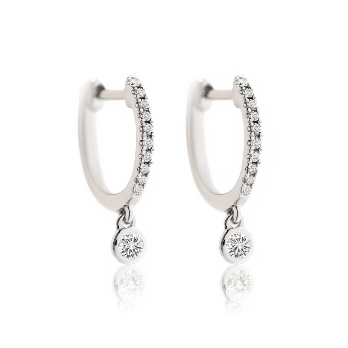 14K white gold pavé huggie hoops with a dangling bezel-set diamond drop, on a white background