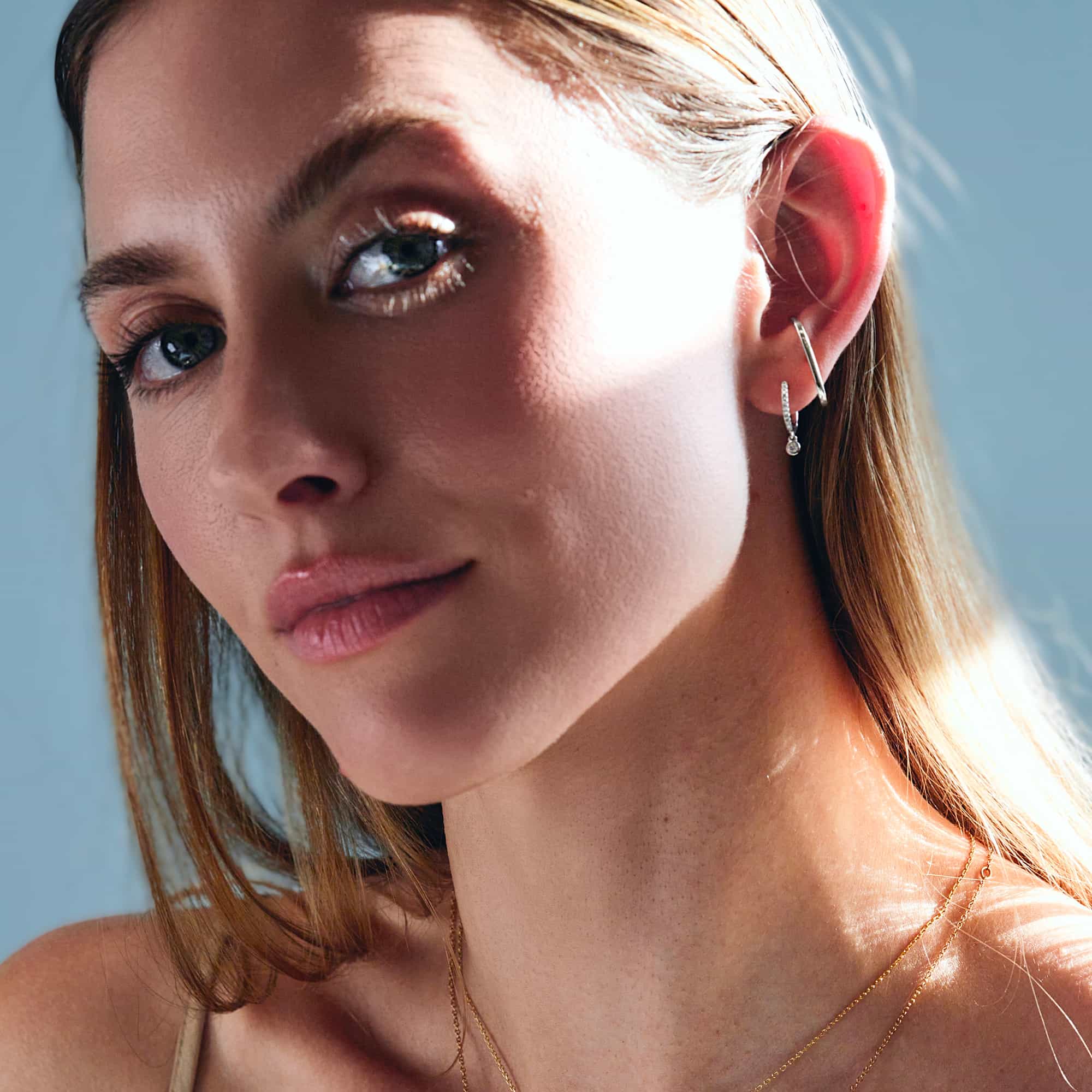 14K white gold diamond drop huggie shown on a model's lobe, side profile view