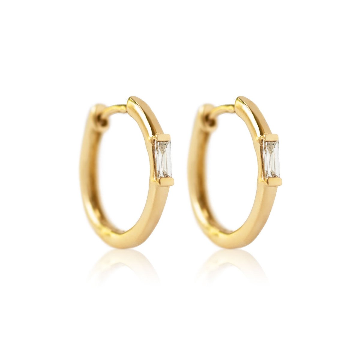 Pair of 14K gold huggie hoops with a baguette diamond, on a white background