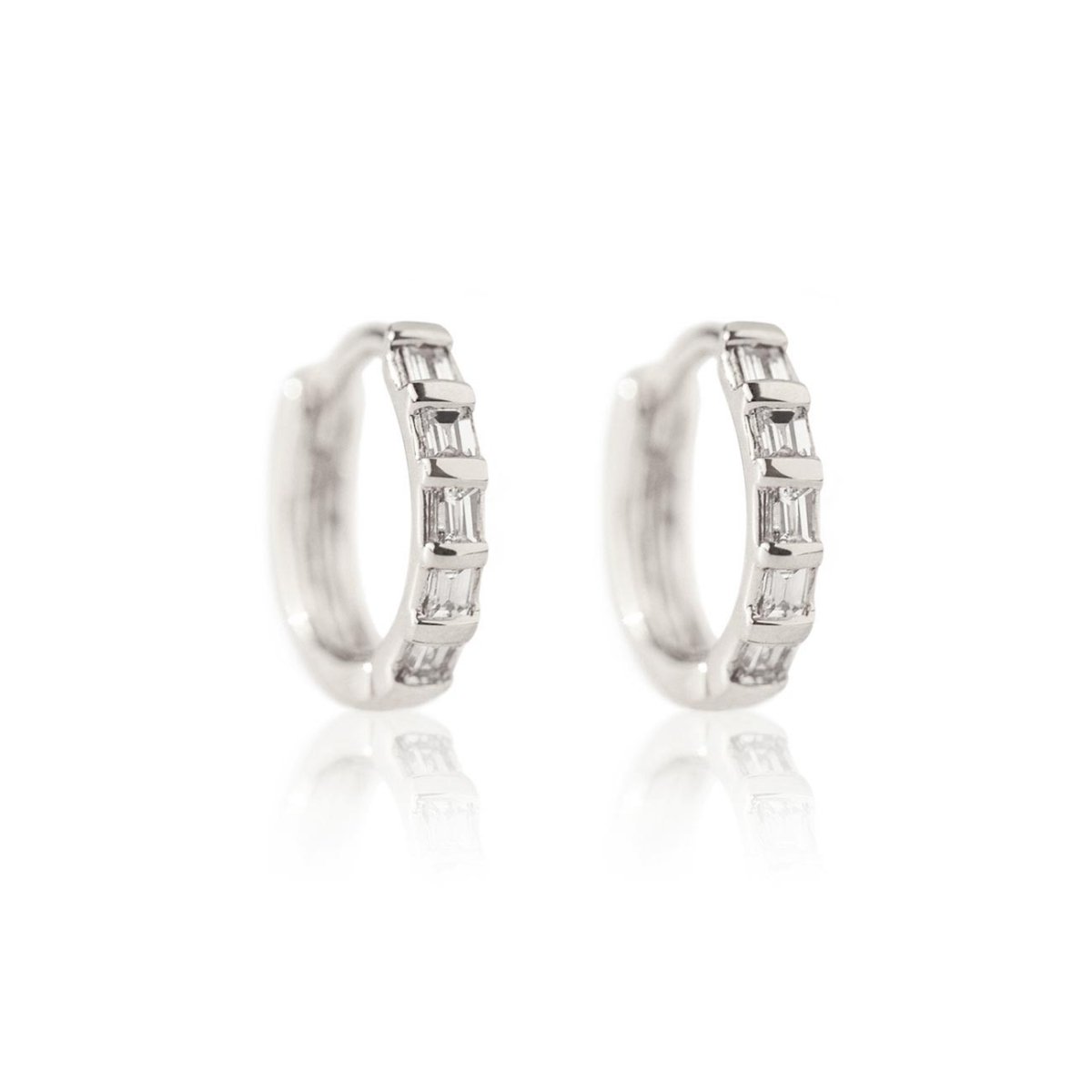 Pair of 14K white gold baguette diamond huggie hoops with clear baguette stones, on a white background
