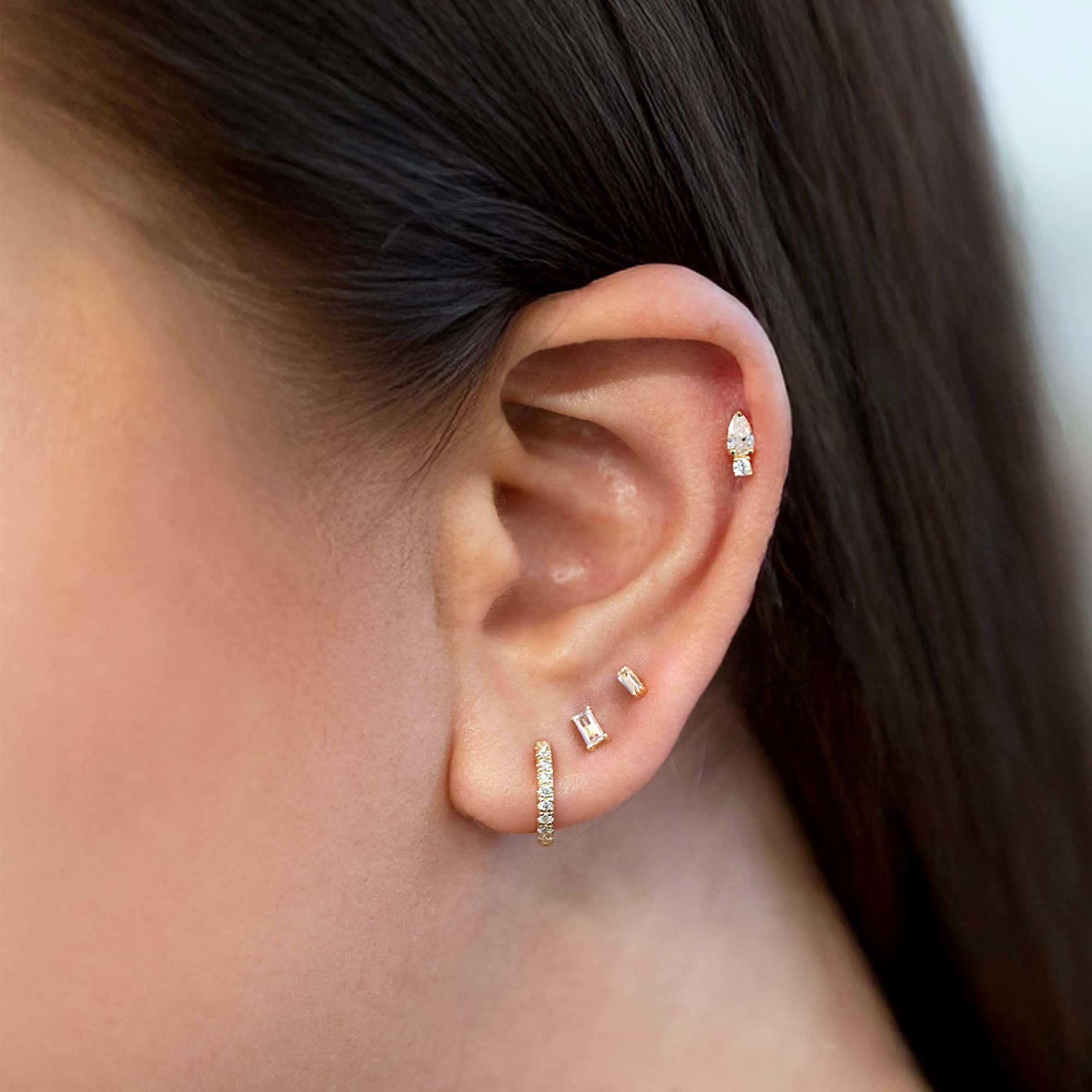 14K gold diamond huggie hoop in a styled ear stack with baguette and pear studs