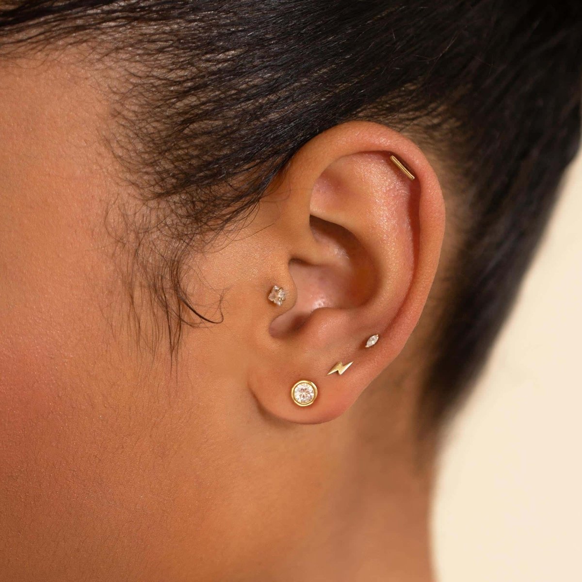 14K gold marquise clear-stone flat back stud shown on a model's lobe with a round bezel stud