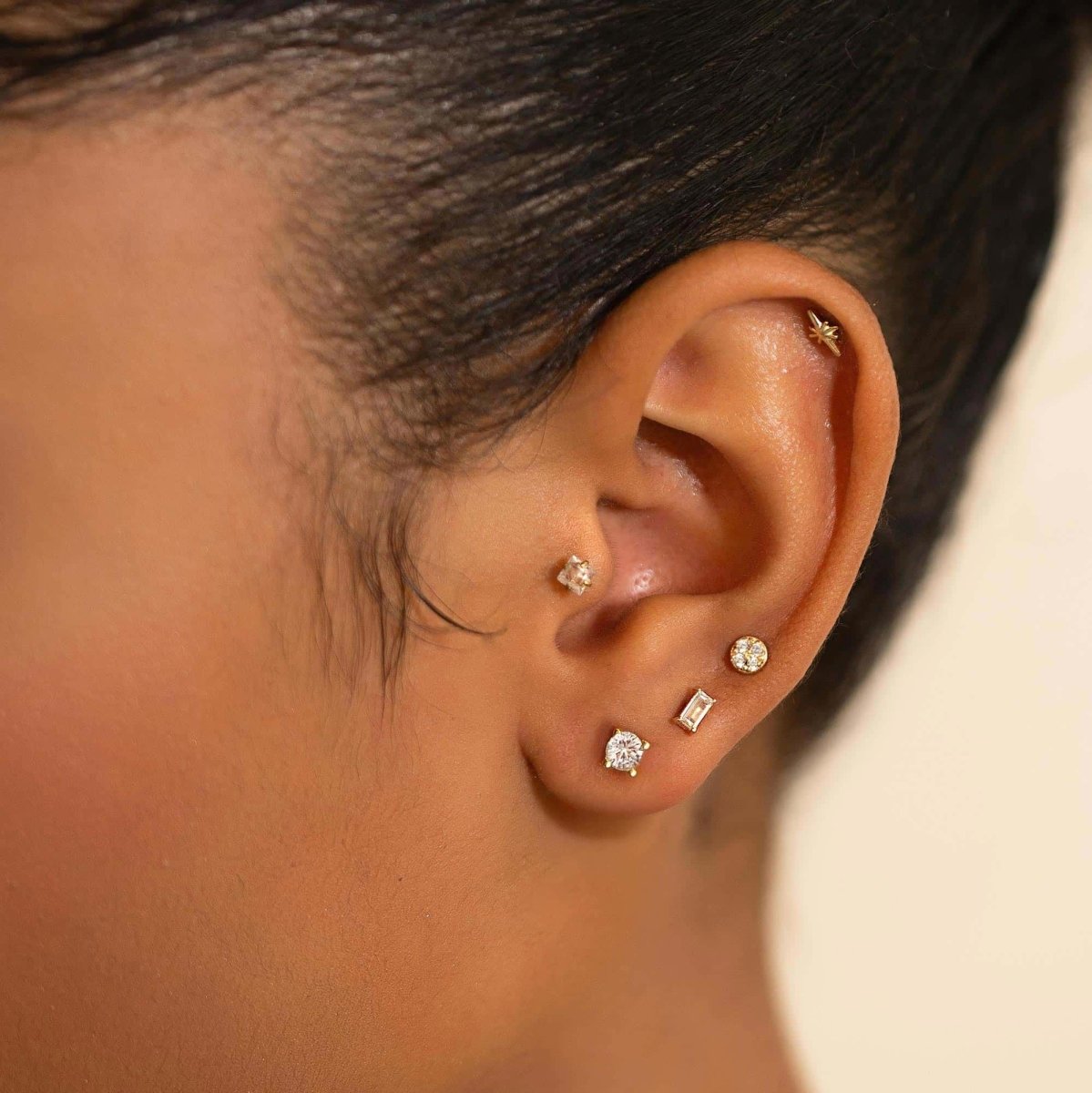 14K gold pavé disc flatback stud with clear stones, shown on a model's lobe in an ear stack